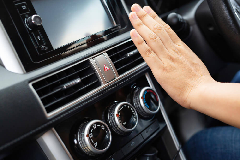 Persona che avvicina la mano al climatizzatore dell'auto per scaldarsi