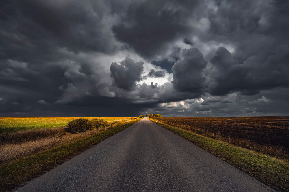 Cielo tempestoso scuro sopra una strada deserta, con nuvole minacciose e un'atmosfera inquietante.