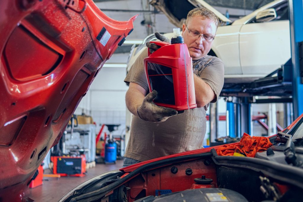 Manutenzione auto in Primavera: uomo che cambia olio di un auto