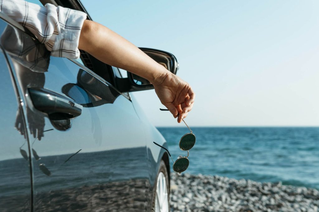 Persona con occhiali da sole in mano, in auto